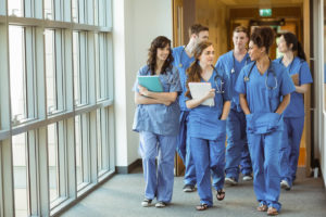 Learn more about studying medicine at an Australian university medical students wearing scrubs walking in hospital