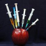 apple with hypodermic needles stuck in it