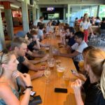 students at a long table with beer