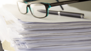 Learn more about how to apply to an Australian university! stack of paperwork with glasses