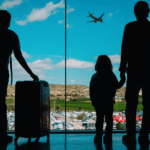 family standing in the airport watching plane take off